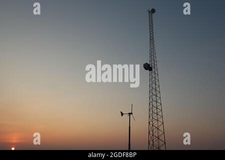 Sendemast mit Parabolantennen,Windrad mit Nabendynamo auf dem Parkplatz vor der Murphy`s Dome Air Force Station Militärbasis in Fairbanks,Alaska,USA. Stockfoto